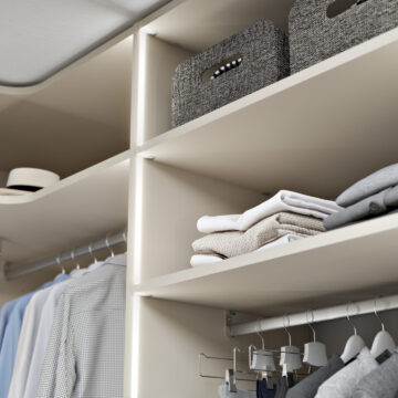 Interior of a built-in wardrobe with shelves and integrated lighting.