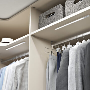Interior of a built-in wardrobe with shelves and lighting.